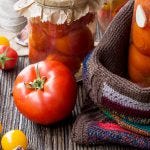 Fresh Tomatoes Beside Jars of Canned Tomatoes
